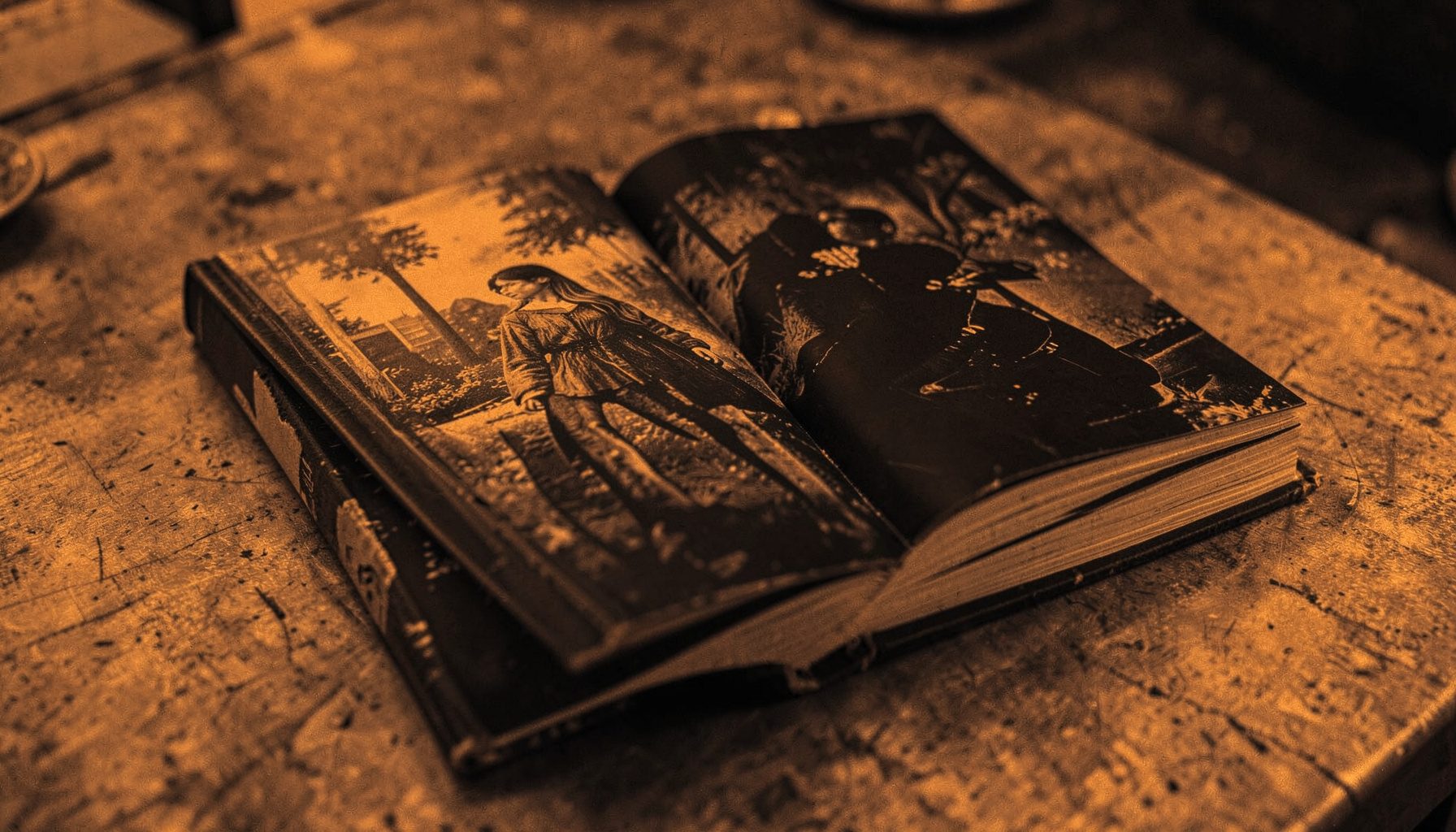 A duotone shot of a thick hardcover graphic novel lying open on a textured tabletop, warm amber and charcoal hues.