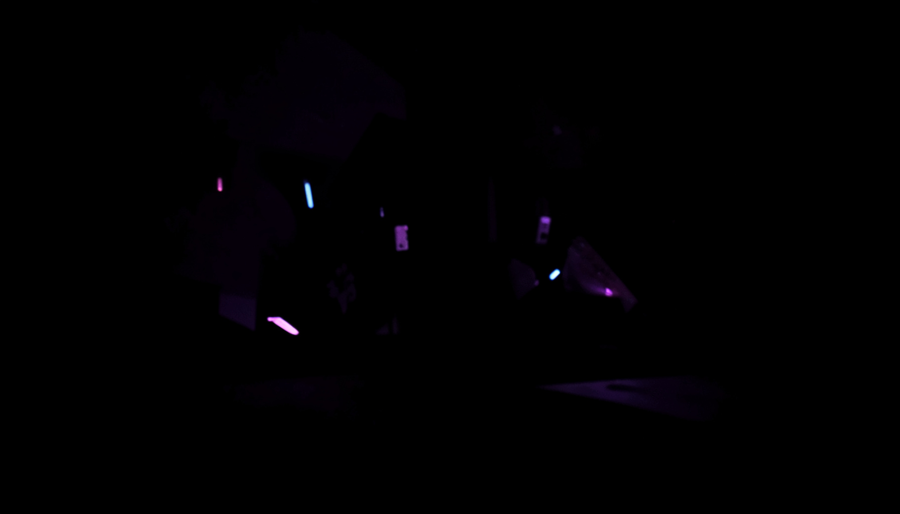 A dark atmospheric scene with glowing neon purple and blue highlights against a black background, evoking the immersive mood of interactive digital entertainment.