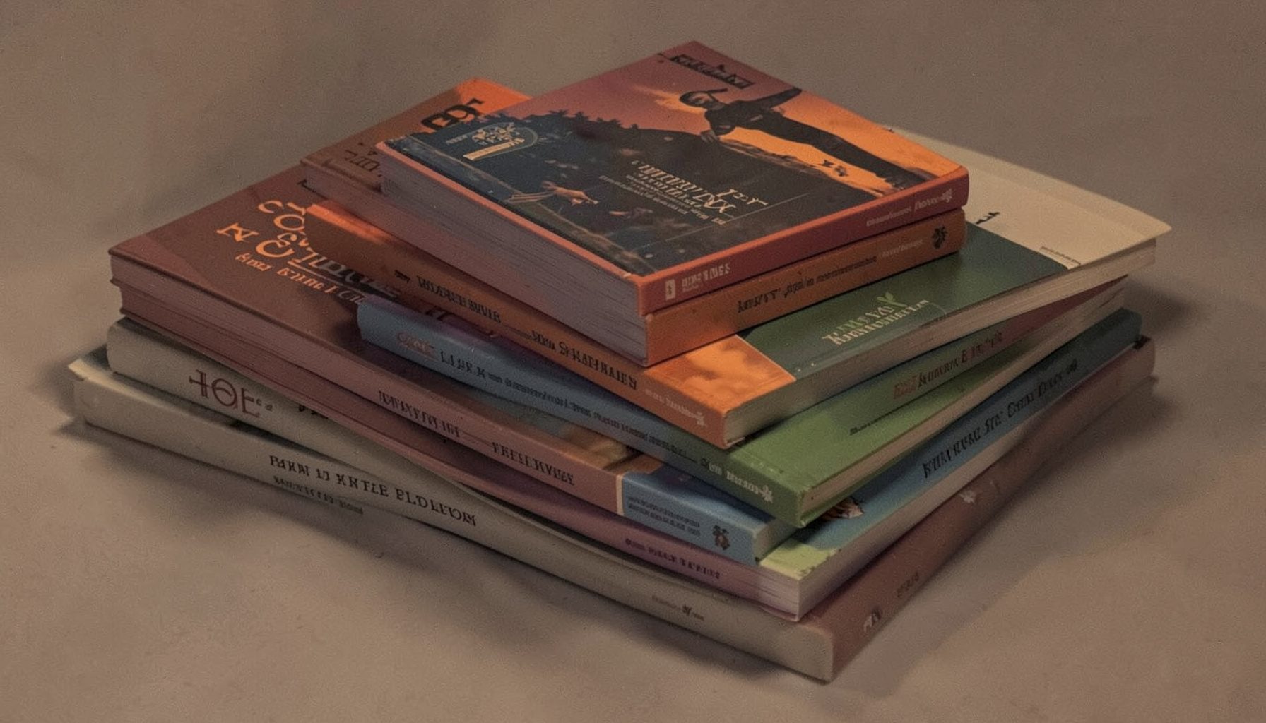 Stack of paperback novels with varied covers in muted reds, blues, and greens